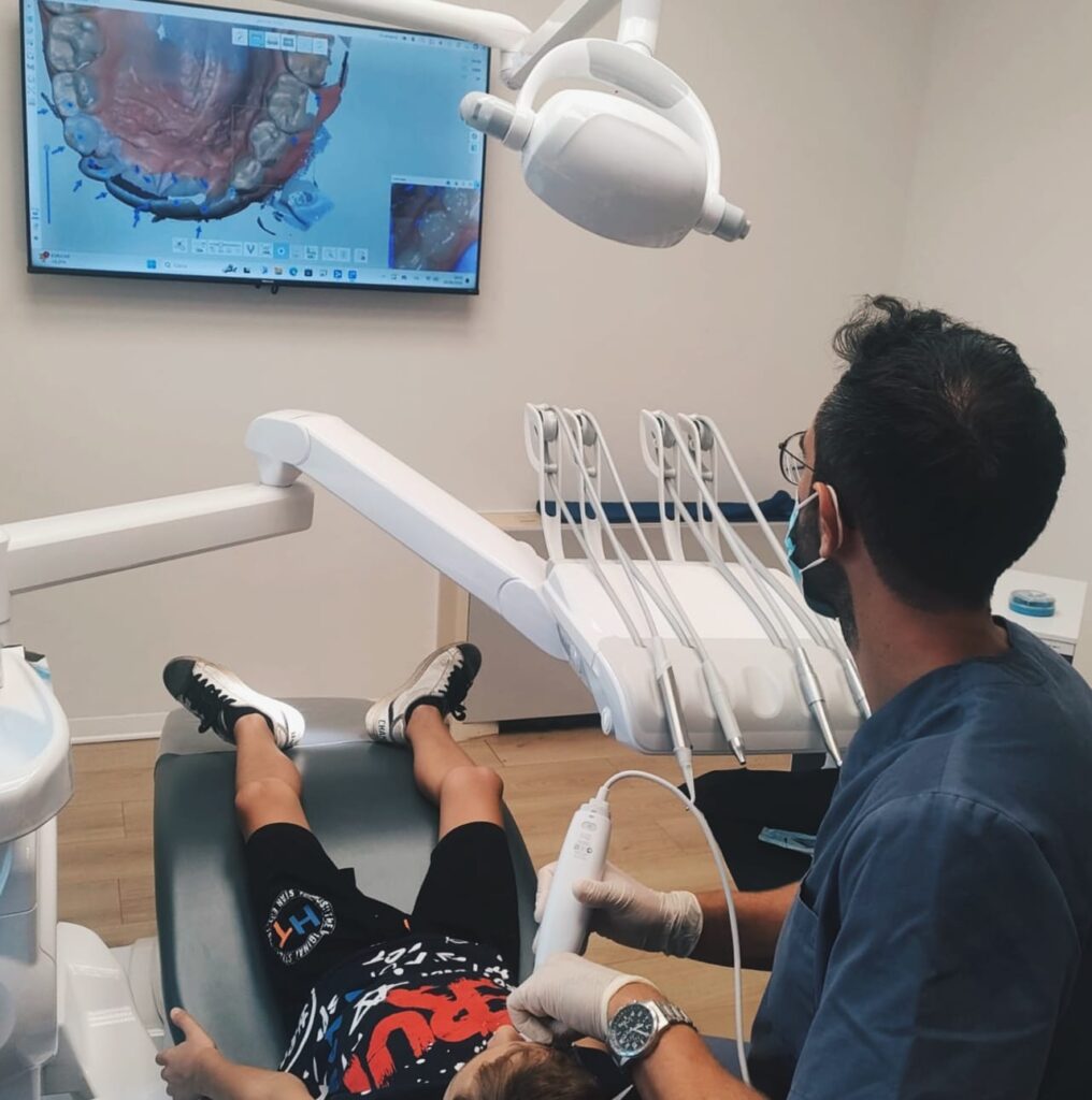 Dentista che utilizza uno scanner intraorale 3D per prendere l'impronta digitale senza fastidio a un bambino allo studio Monti Dental Center di Poggibonsi. Lo schermo mostra l'immagine digitale dei denti